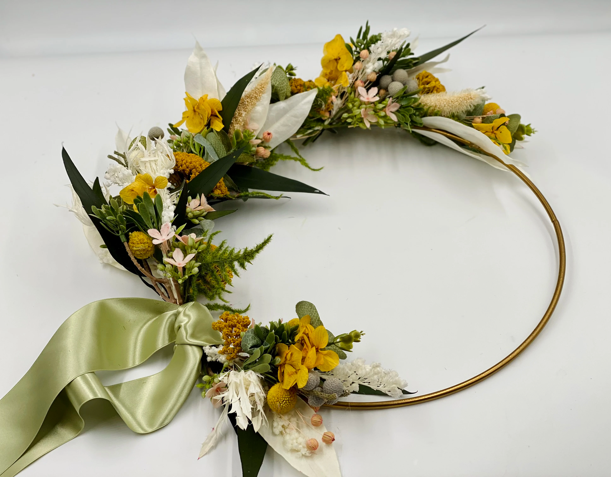 Clementine Wreath: a gold hoop with one side covered in yellow and white flowers with a light green ribbon