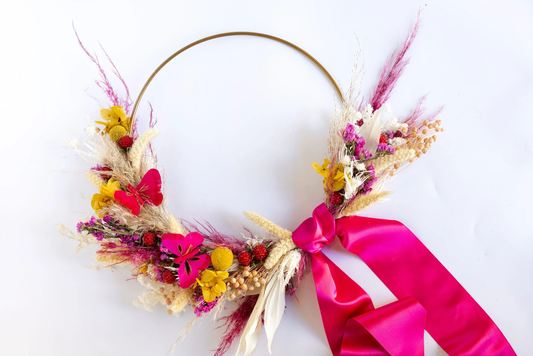 Clementine Wreath: a gold hoop with one side covered in yellow, cream, and bright pink flowers with a hot pink ribbon
