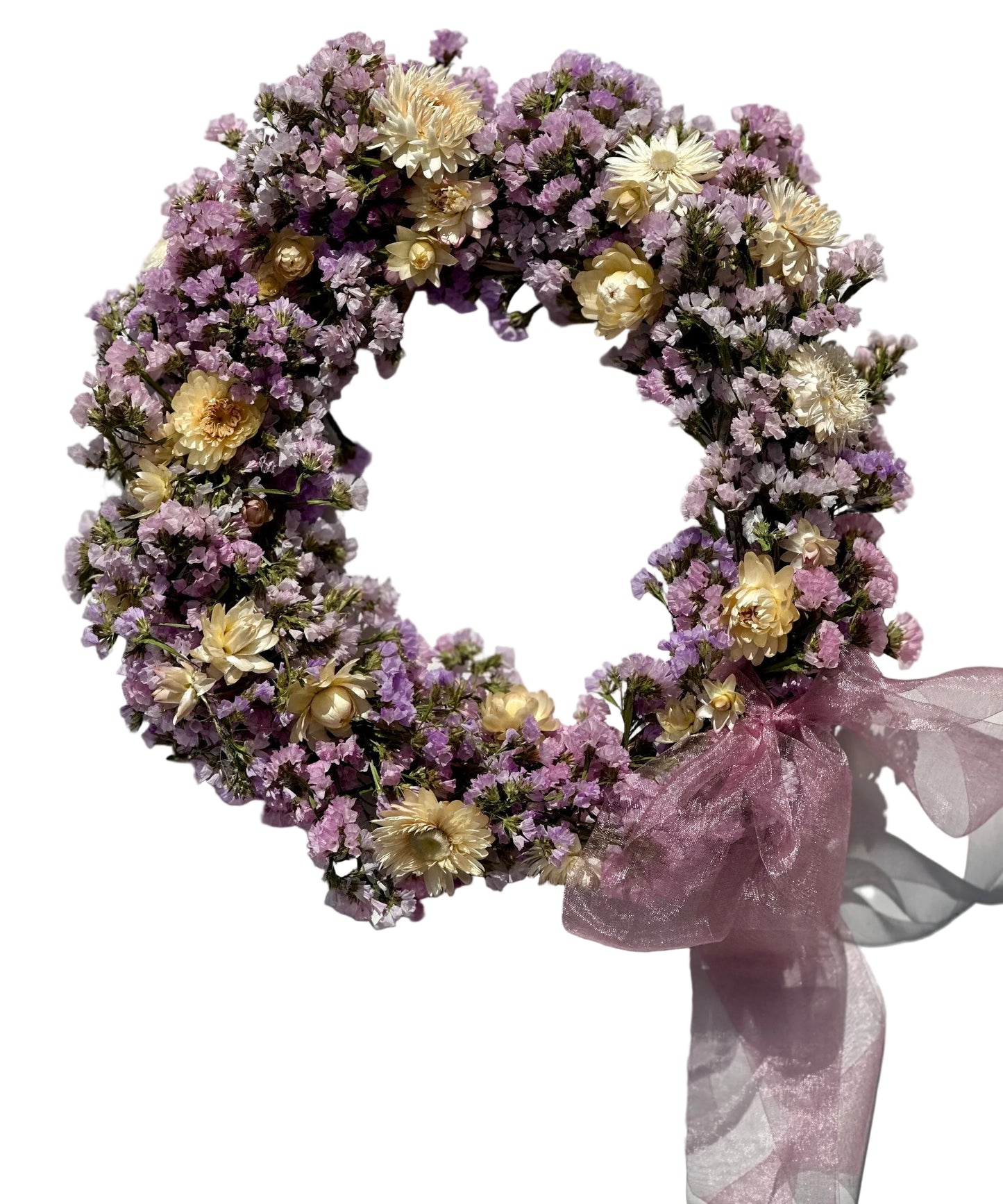 Eloise Wreath: a white wall with a wreath of dried lavender statice and dried buttercream strawflower adorned with a gauzy lavendar bow