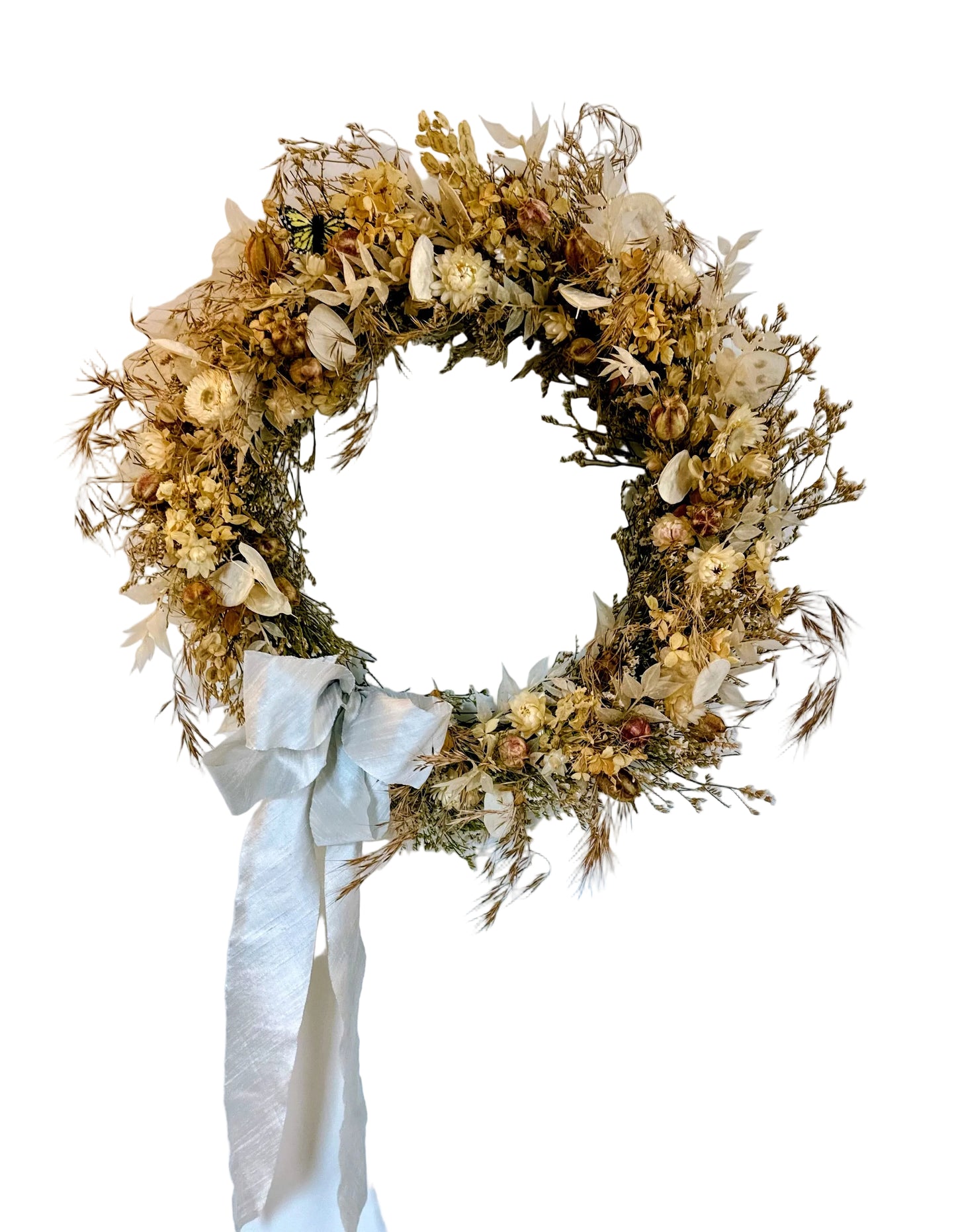 Dried floral wreath with a white ribbon on a white wall