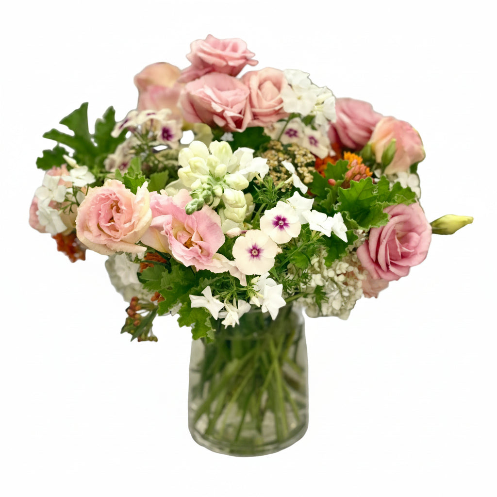 Bouquet of light pink and white flowers in a clear vase against a tiled wall background