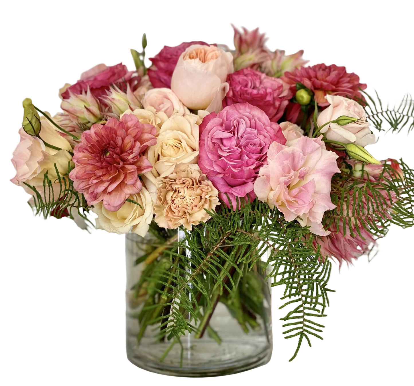 Bouquet of pink, blush, and cream flowers in a clear vase on a light background