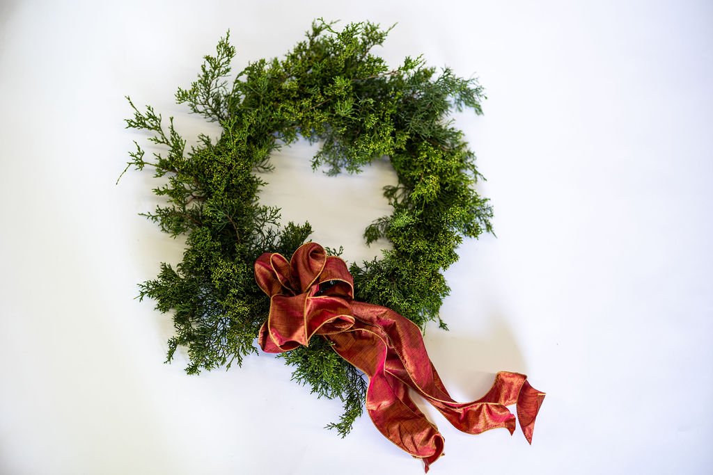 Noelle Wreath: green wreath of cedar and fir with a red bow
